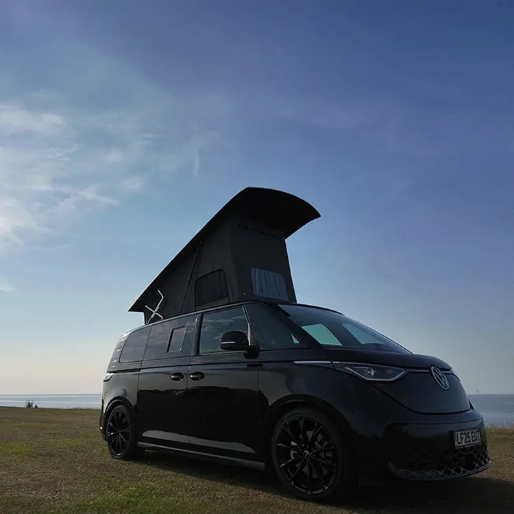 Black VW ID. Buzz with the Horizon pop-top roof raised by the sea